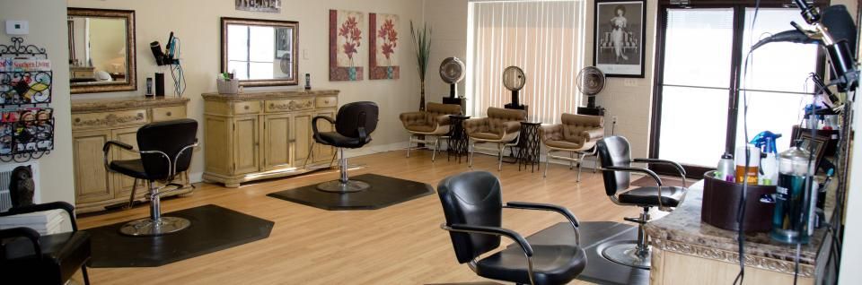 Modern salon interior with black styling chairs, mirrors, tan cabinets, and large windows