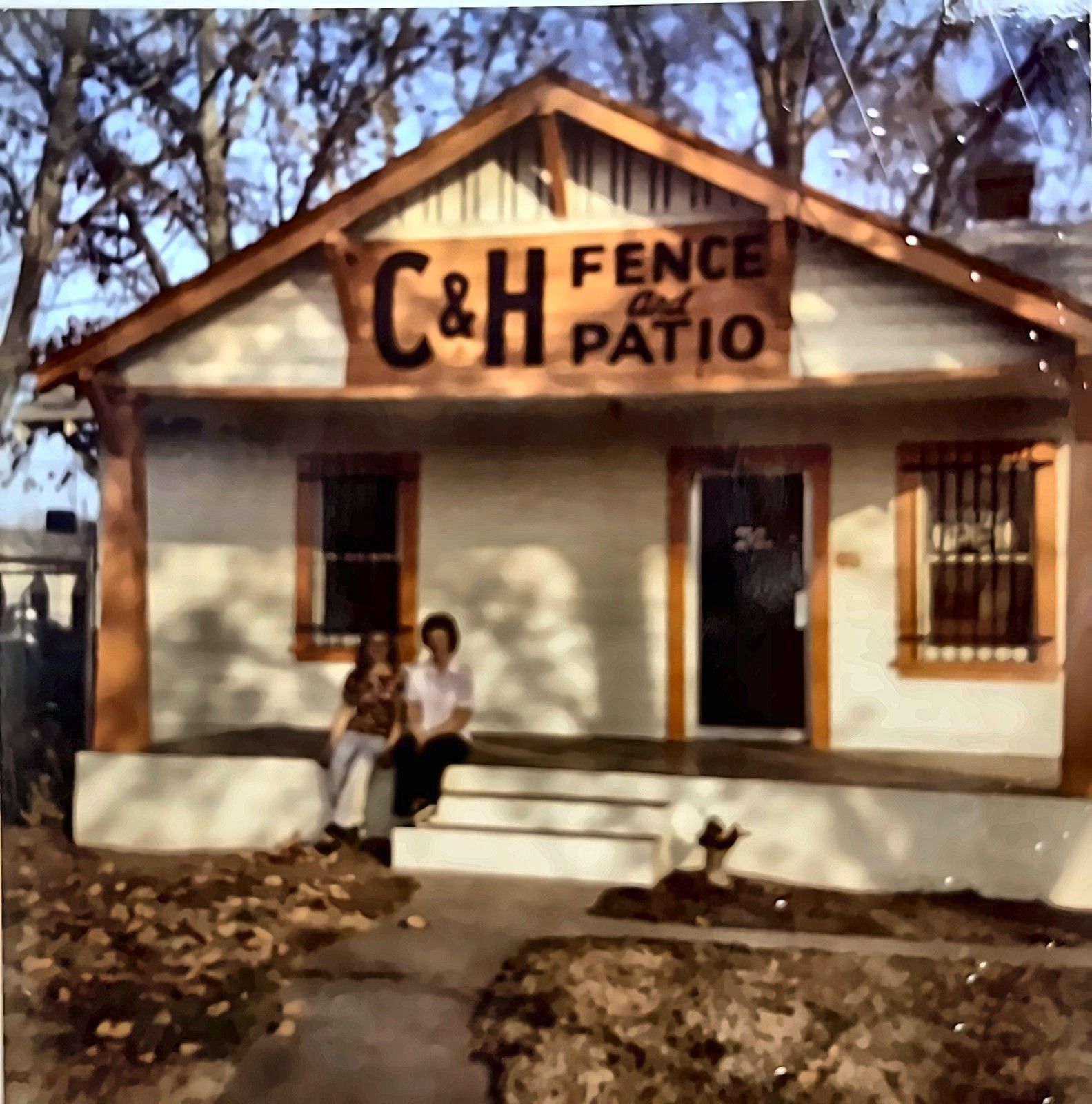 C&H Fence and Patio storefront with two people sitting on the front steps