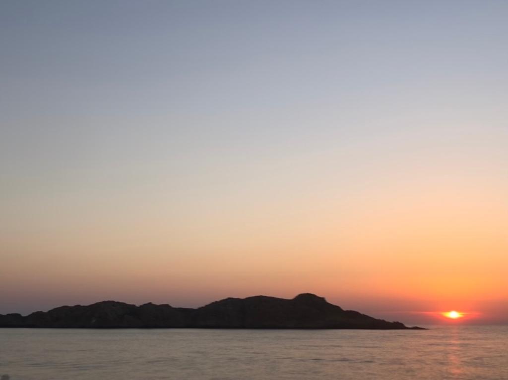 Un tramonto su uno specchio d'acqua con le montagne sullo sfondo