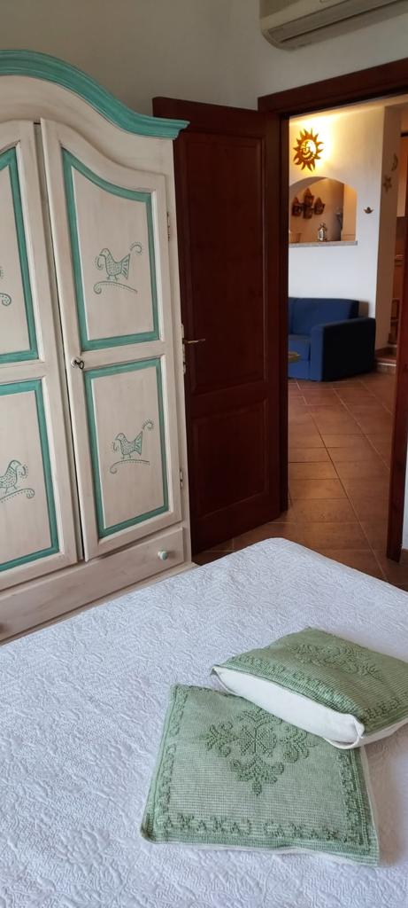 Una camera da letto con un letto, un armadio e una porta che conduce al soggiorno.