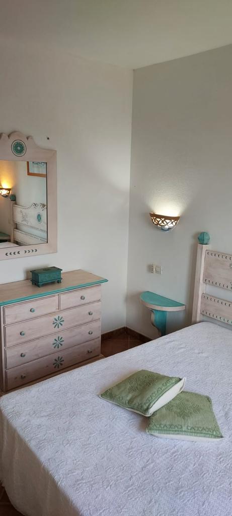 Una camera da letto con un letto, una cassettiera, uno specchio e un tavolo.