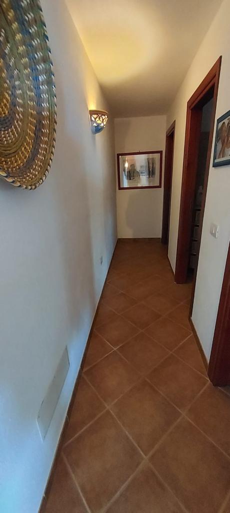 Un lungo corridoio con pavimenti piastrellati e un quadro alla parete.