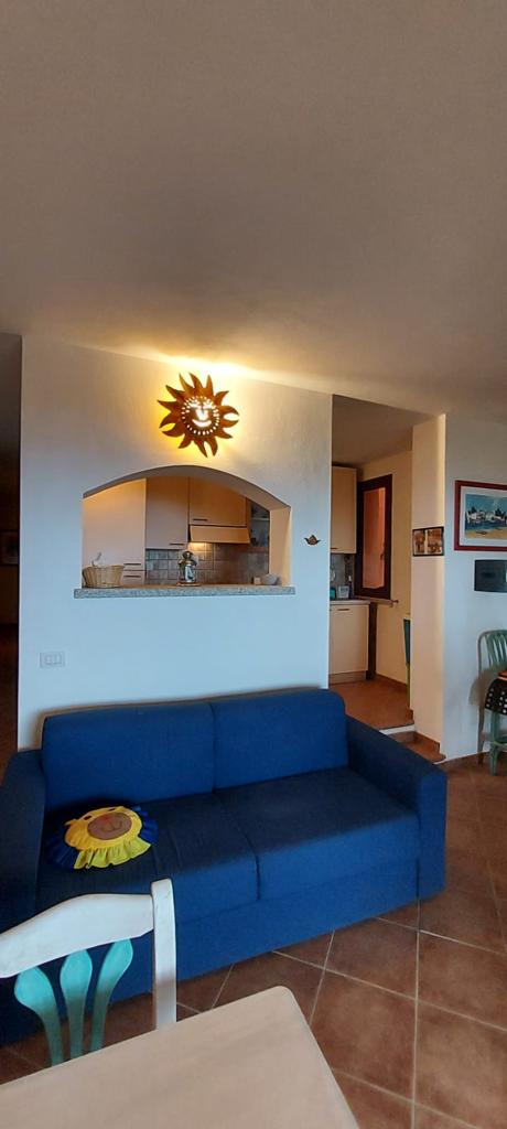 Un soggiorno con un divano blu e un sole sul muro.