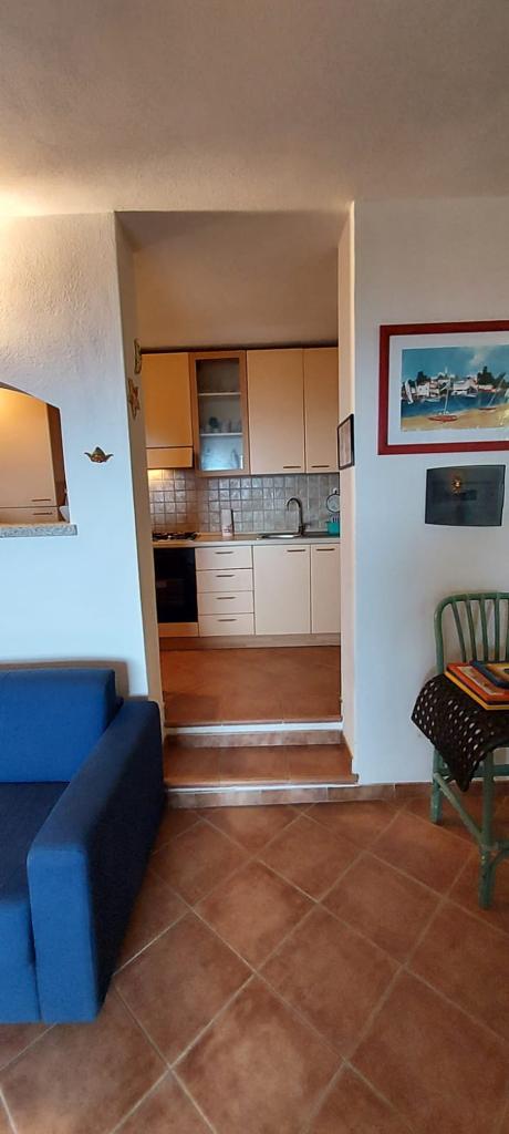 Un soggiorno con un divano blu e una cucina.