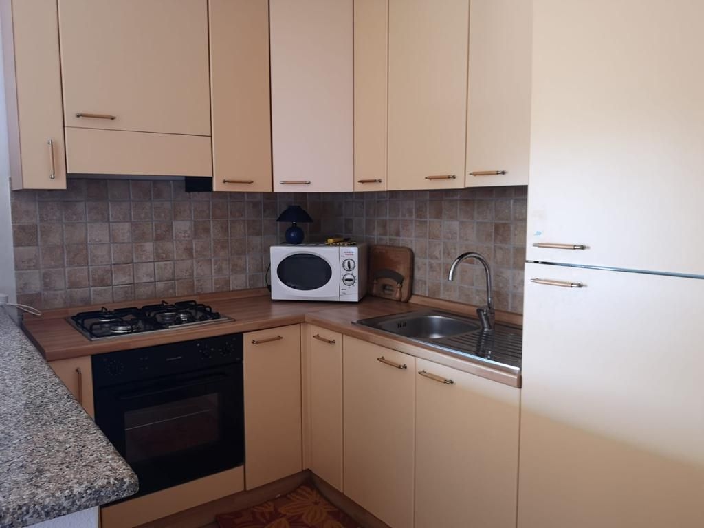 Una cucina con mobili bianchi e un forno a microonde sul bancone