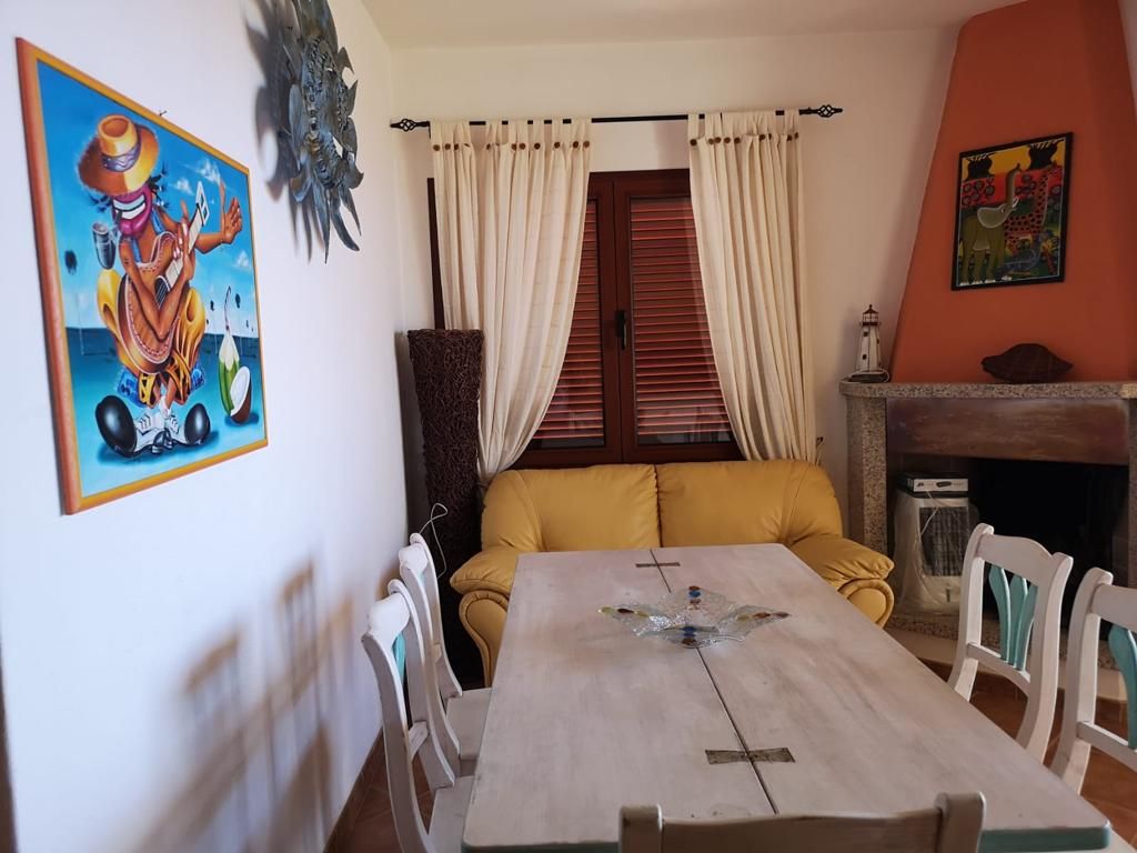 Un soggiorno con tavolo, sedie e un quadro sul muro