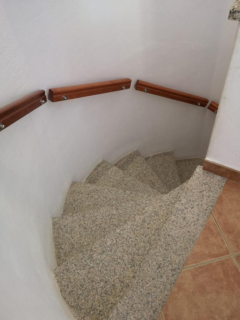 Una scala a chiocciola con corrimano in legno e pavimento piastrellato