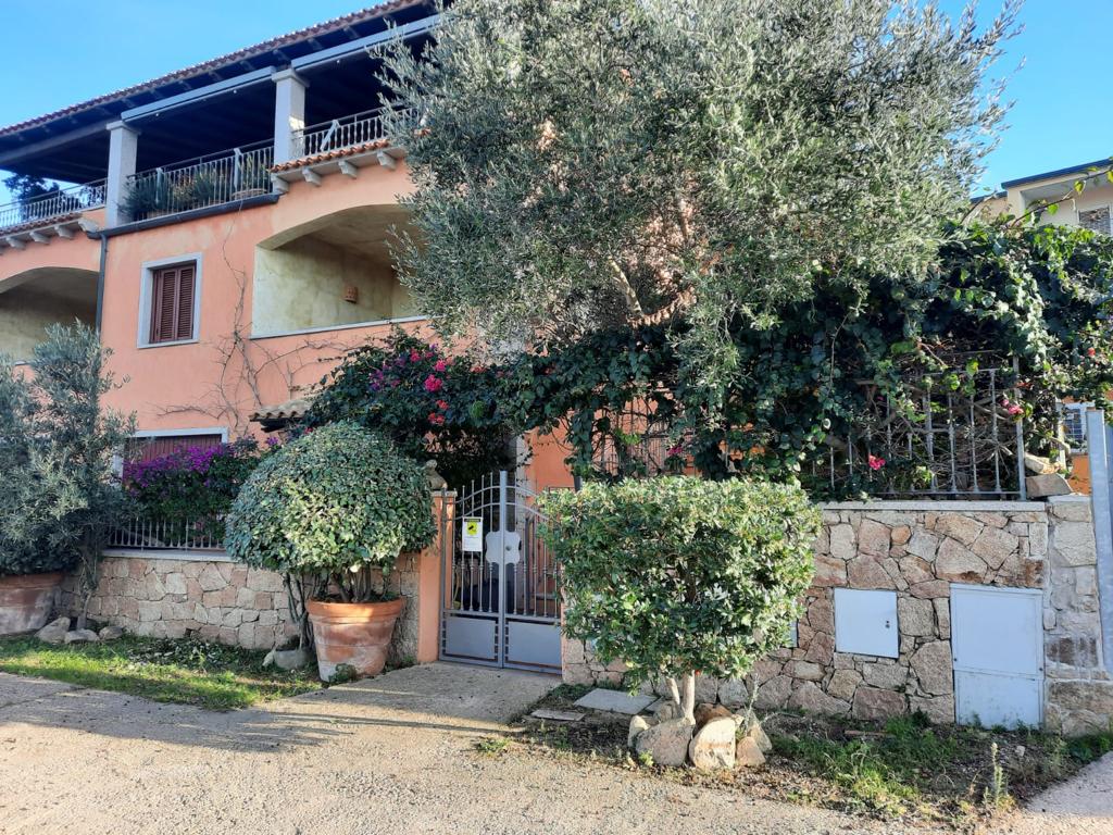 Una grande casa con una recinzione e degli alberi davanti.