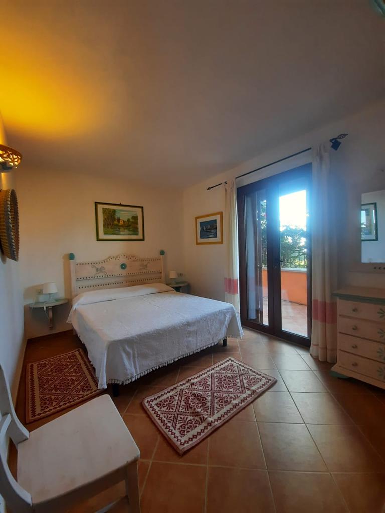 Una camera da letto con un letto grande, una sedia, una cassettiera e uno specchio.