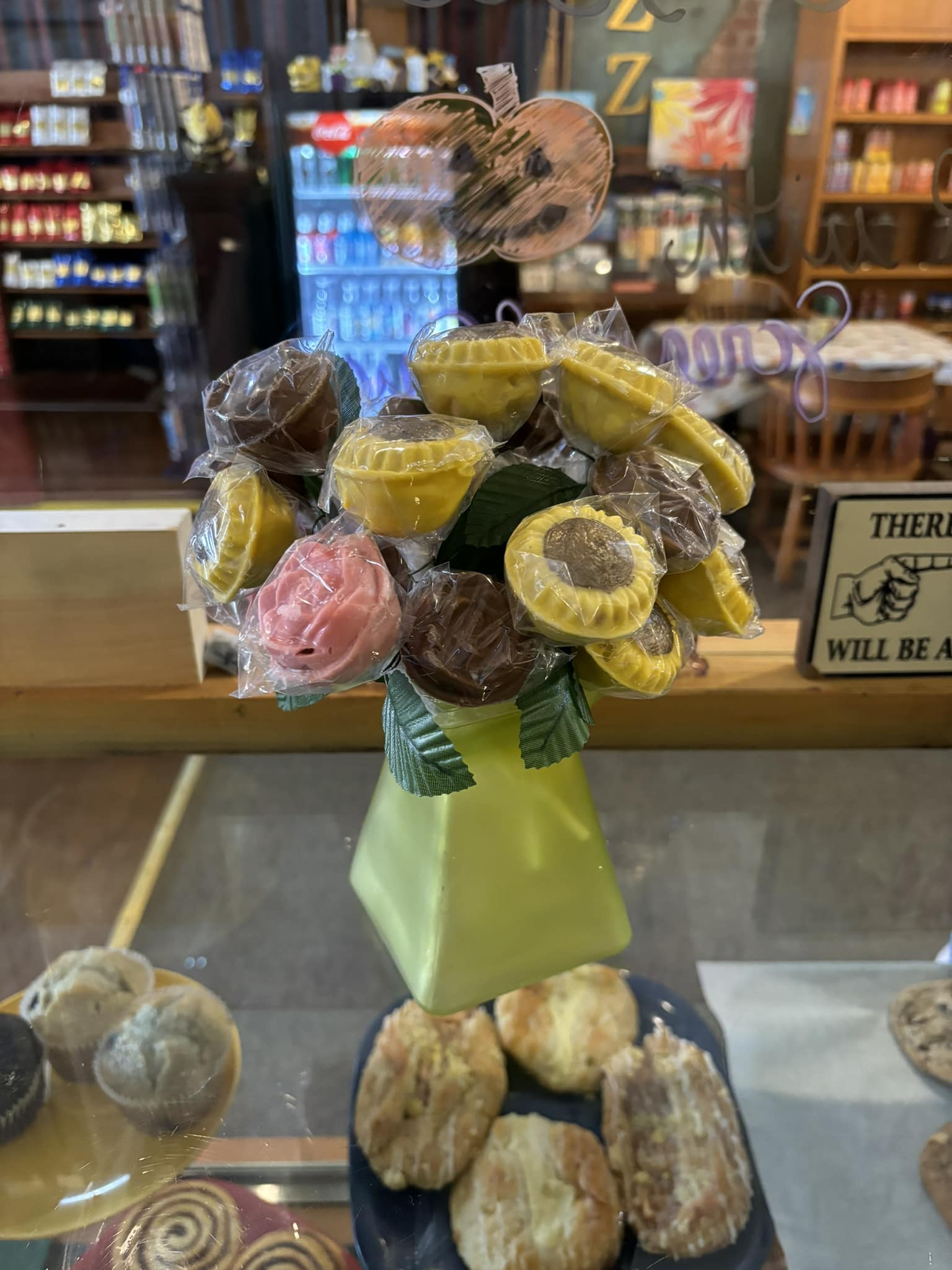 Candy bouquet in a yellow vase on display in a store, with treats visible on the shelves.
