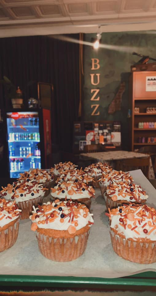 Cupcakes with white frosting and toppings displayed on a counter, with 