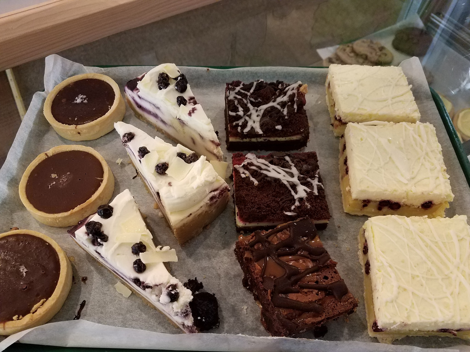 Tray of baked goods: tarts, cheesecake, brownies, and bars.