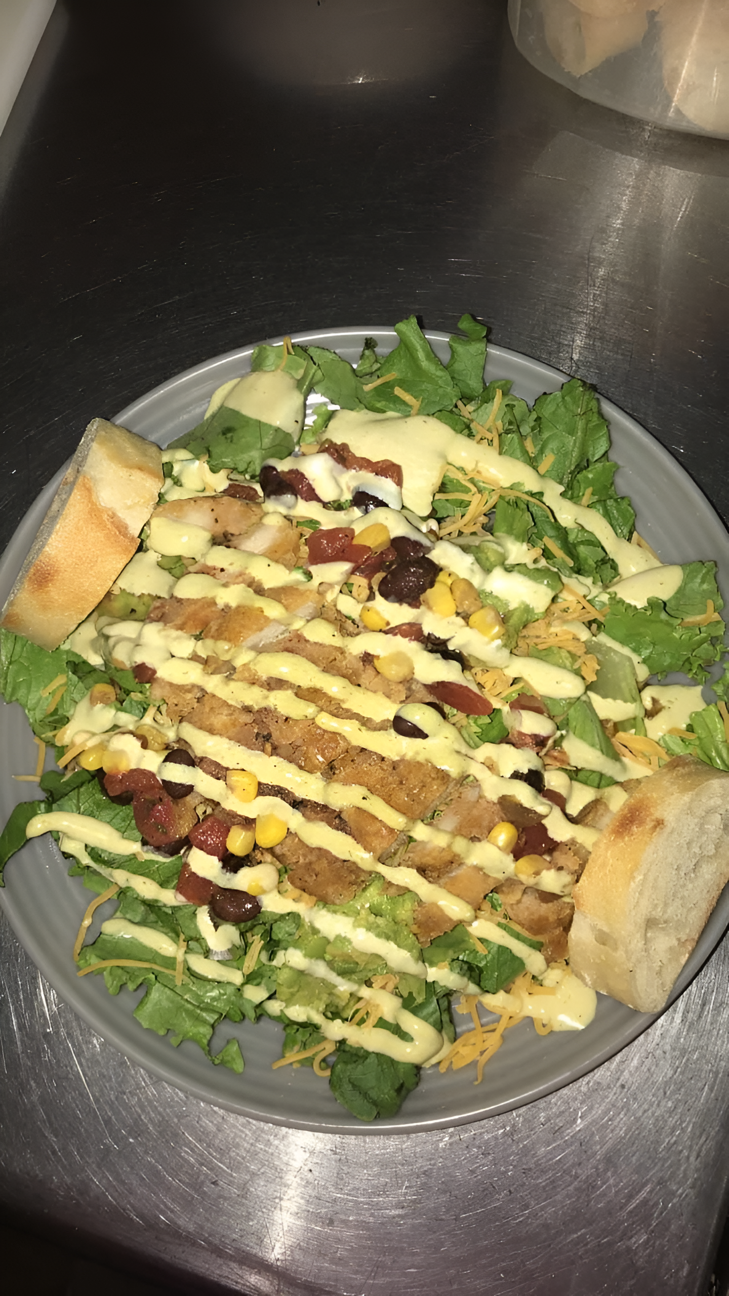 Salad with bread slices and drizzled sauce on a gray plate.