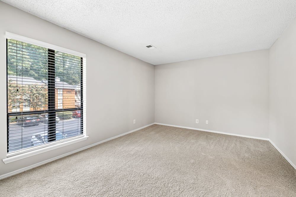 An empty bedroom with a large window and blinds at Marquis at Perimeter Center in Atlanta, GA.