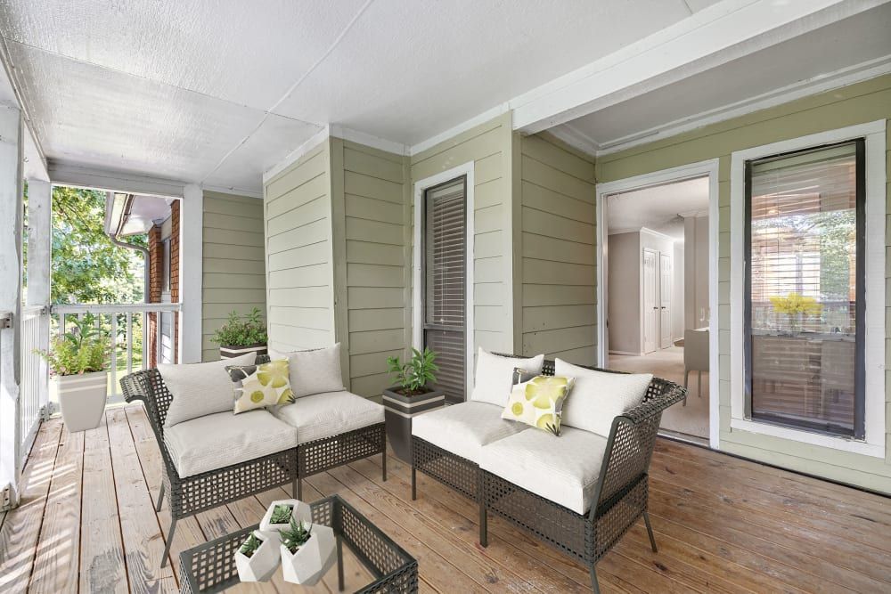 Apartment patio/balcony with a couch, chairs, and a table at Marquis at Perimeter Center in Atlanta, GA.