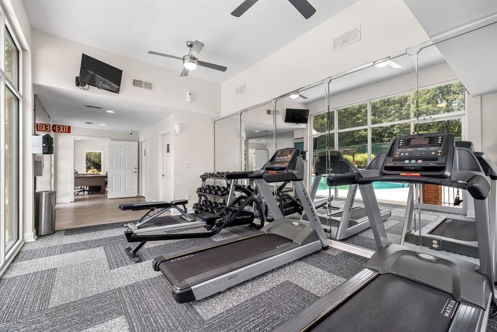 A 24-hour fitness center with treadmills, dumbbells, and oversized windows at Marquis at Perimeter Center in Atlanta, GA.