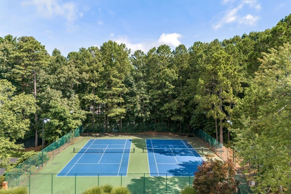 Outdoor tennis court surrounded by trees at Marquis at Perimeter Center in Atlanta, GA. 