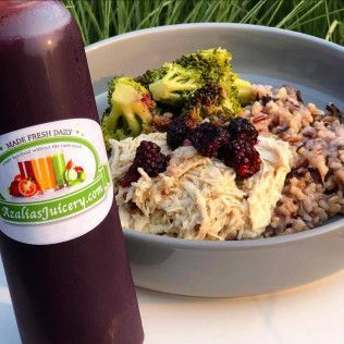 Juice bottle beside a bowl of oatmeal topped with berries and broccoli on a table