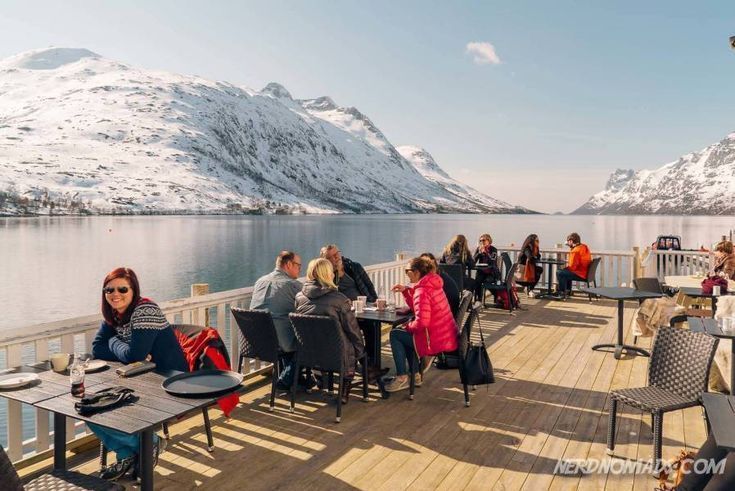 people sitting onboard od a cruise in a tromso port drinking coffe and the landscape is covered in snow