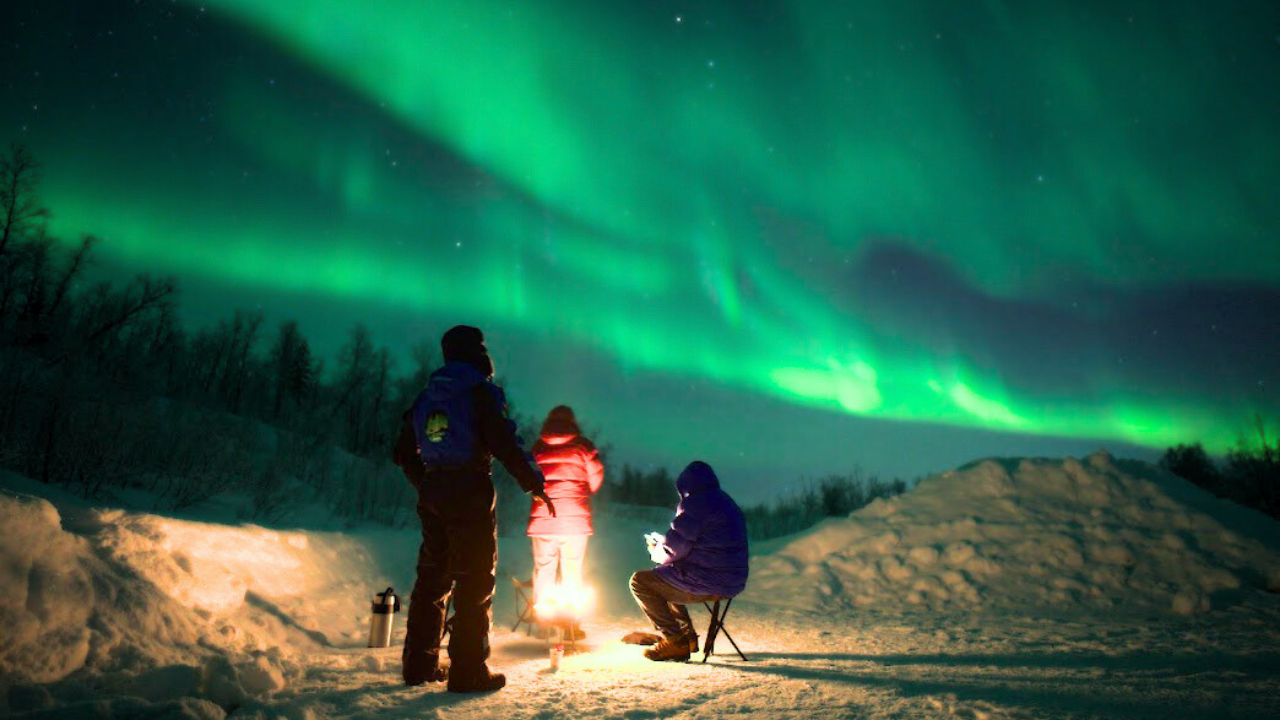 aurora northern lights group beside camp fire