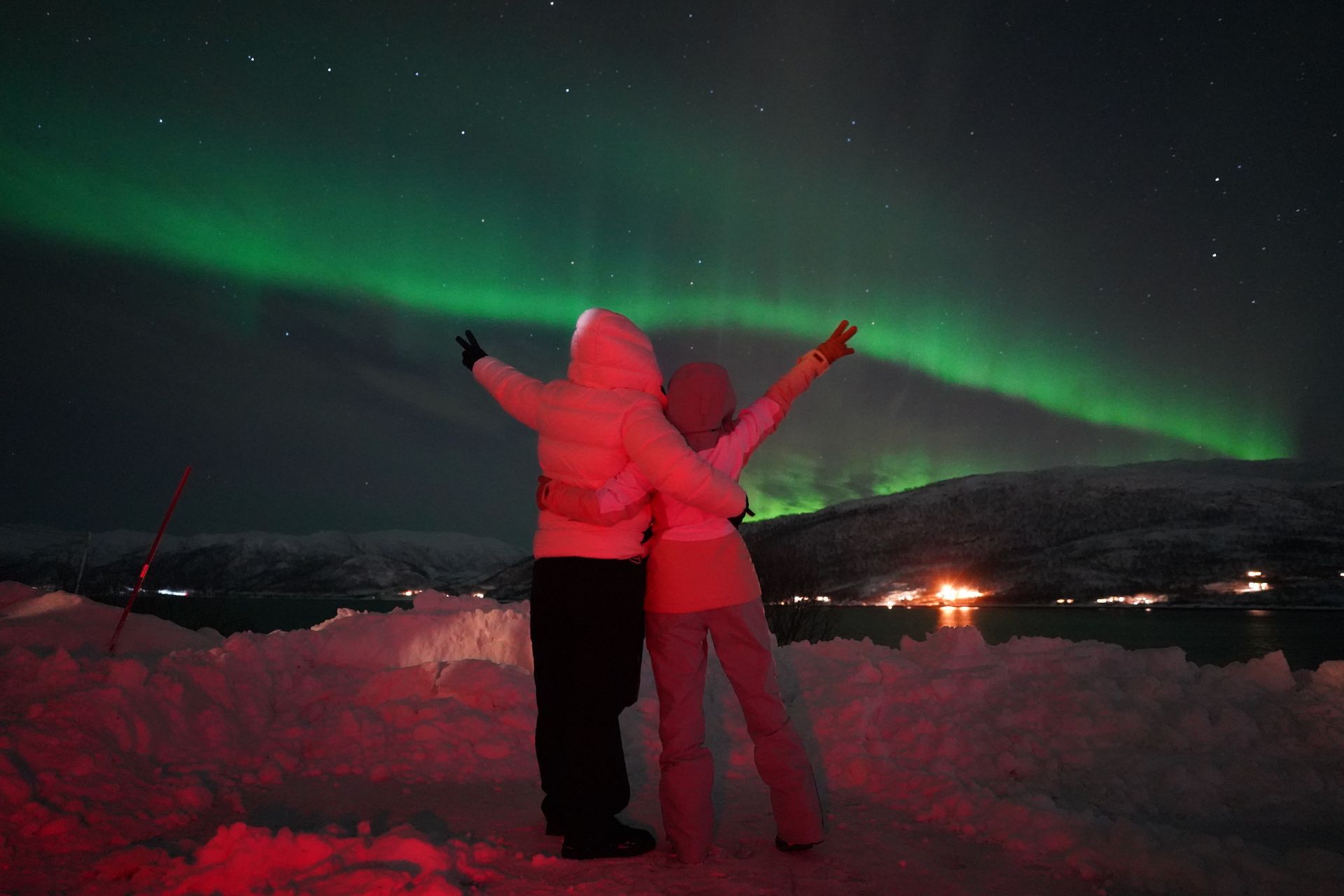 couples holding hands under the northern light sky in tromso norway