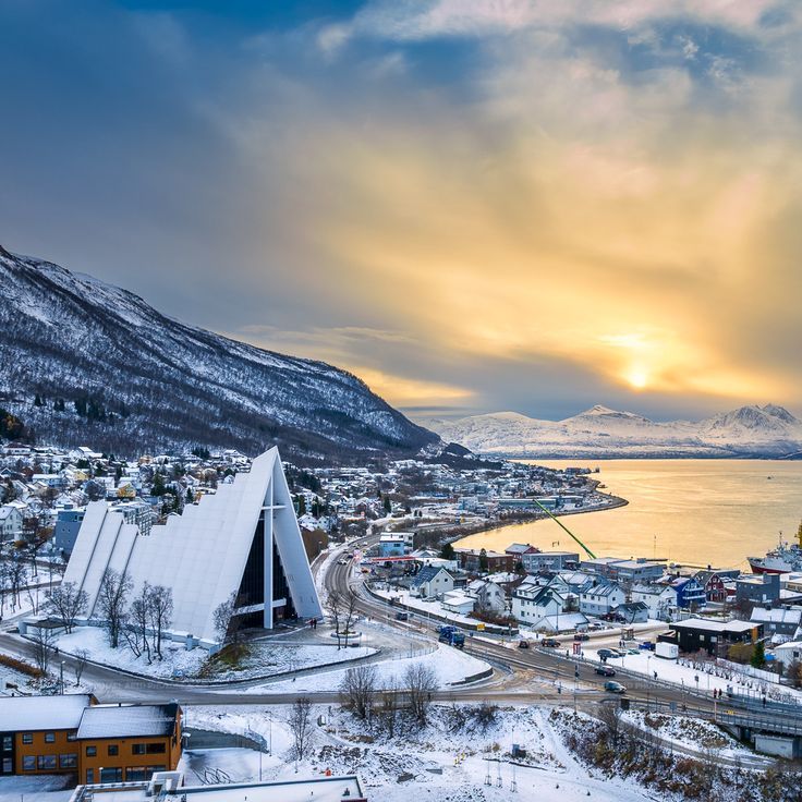 Tromso Cathedral and the midnight sun in the background and the mountain covered in snow