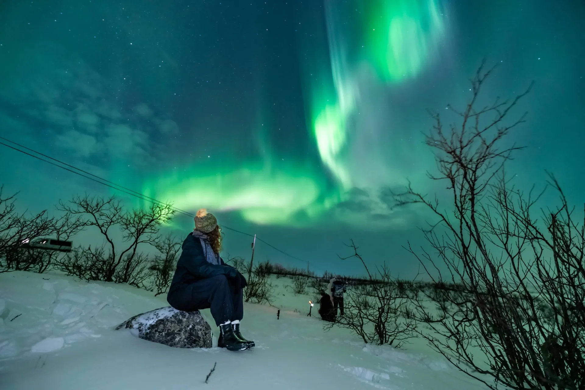 couples standing infront of mesmerizing northern light sky in tromso norway