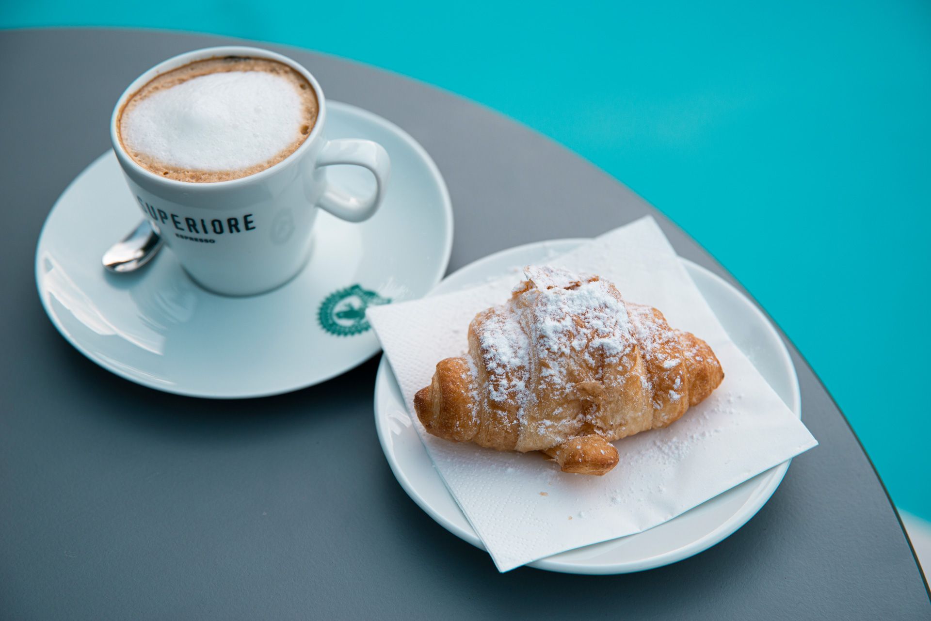 Una tazza di caffè e un croissant su un piatto su un tavolo.