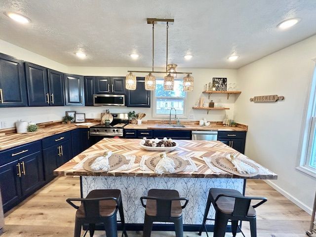 Navy blue kitchen with wood counters, island, and gold accents.