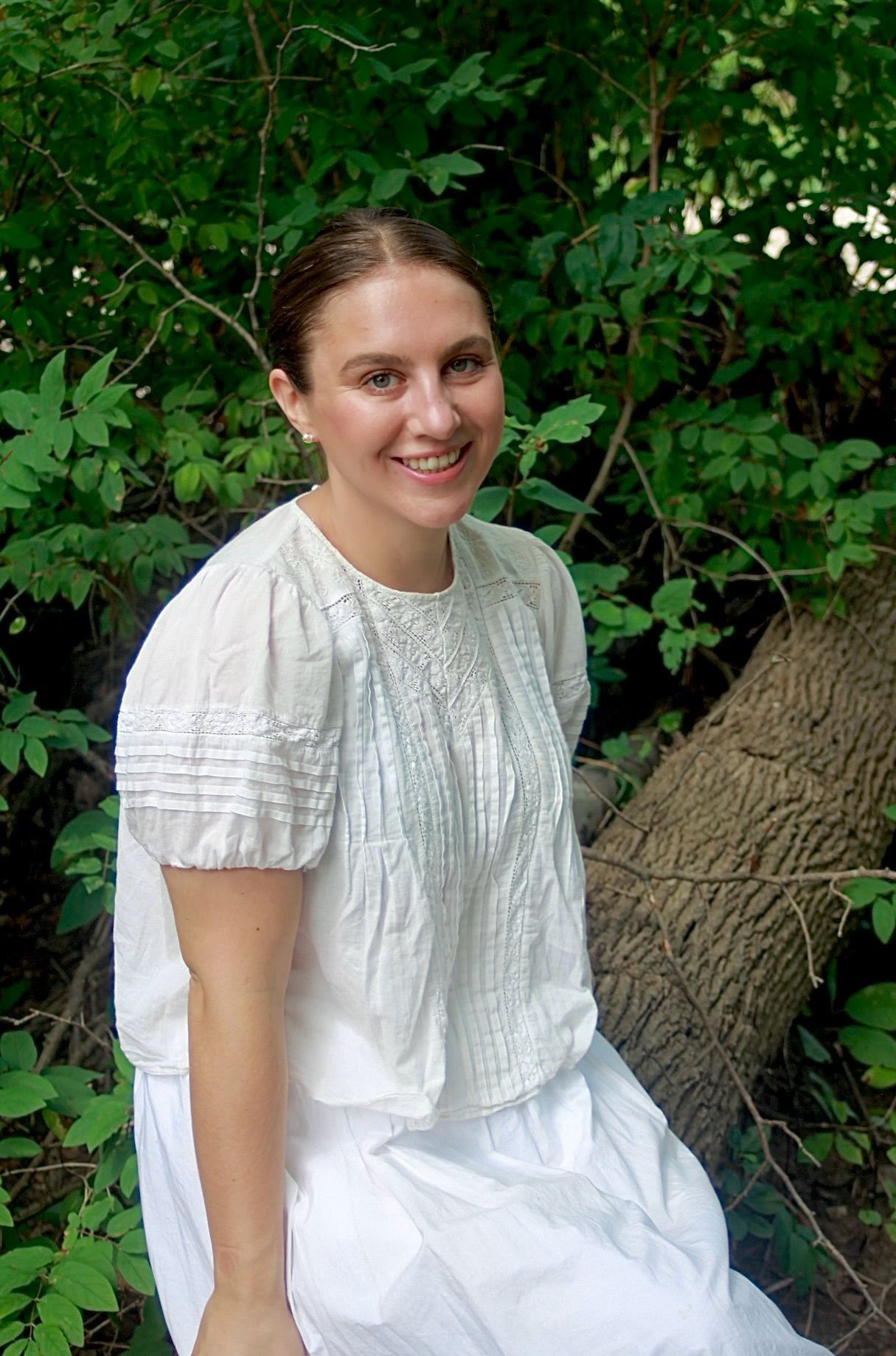 A woman wearing a grey cardigan and a green shirt is smiling for the camera.