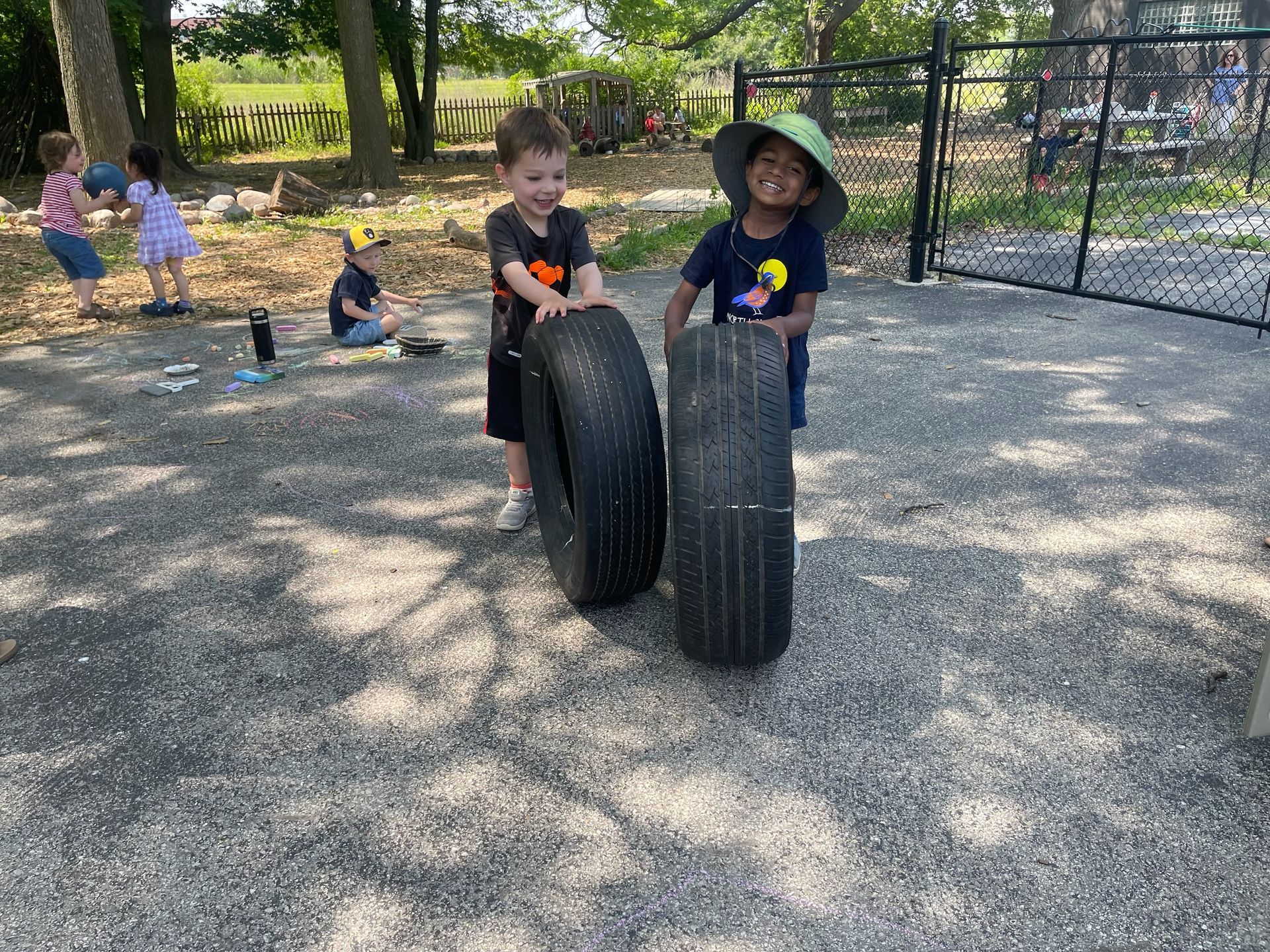 Two young boys are playing with tires in a park.