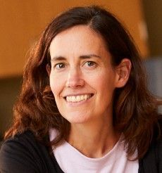 A woman with long brown hair is smiling for the camera.