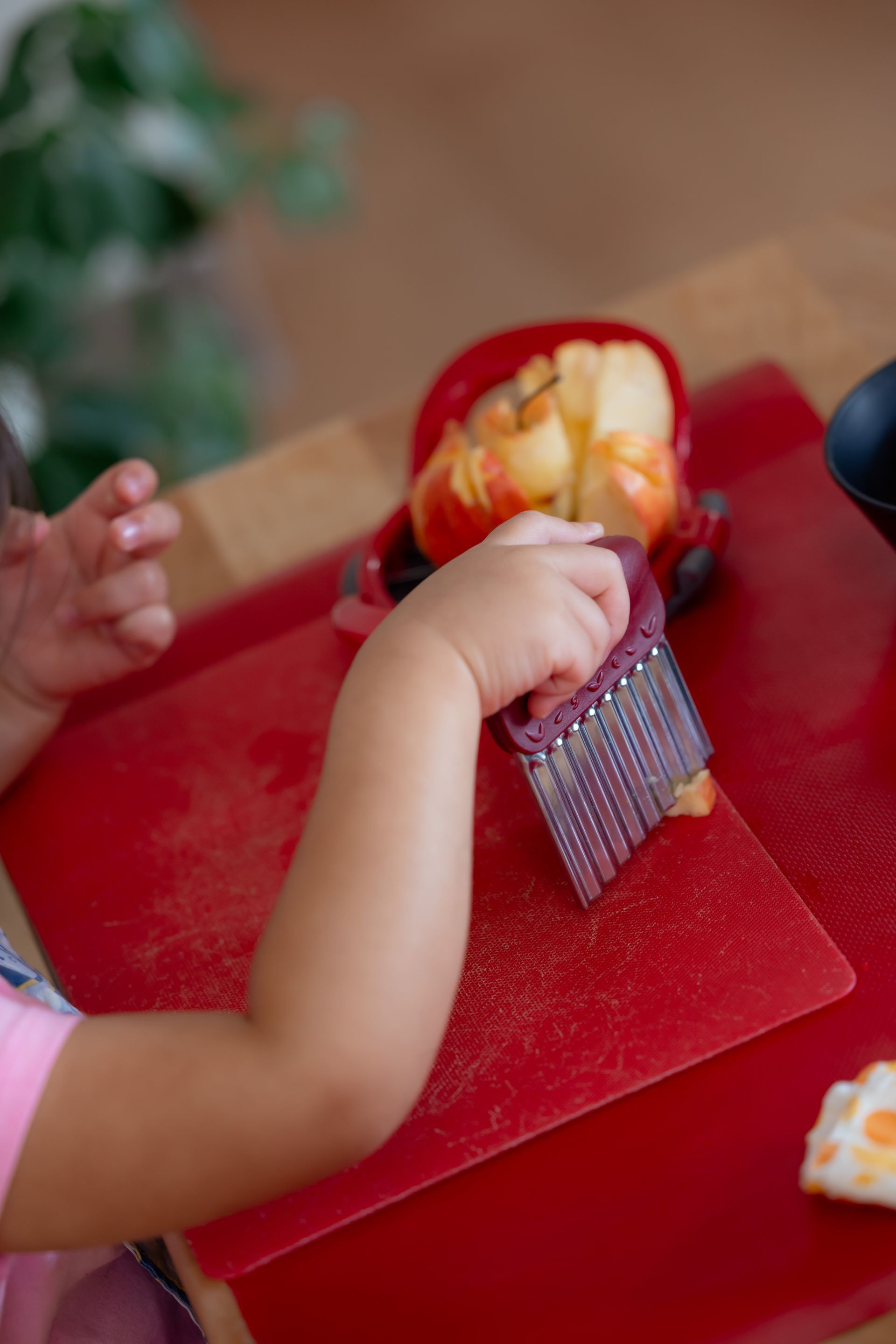 Child working on food prep at a red table
