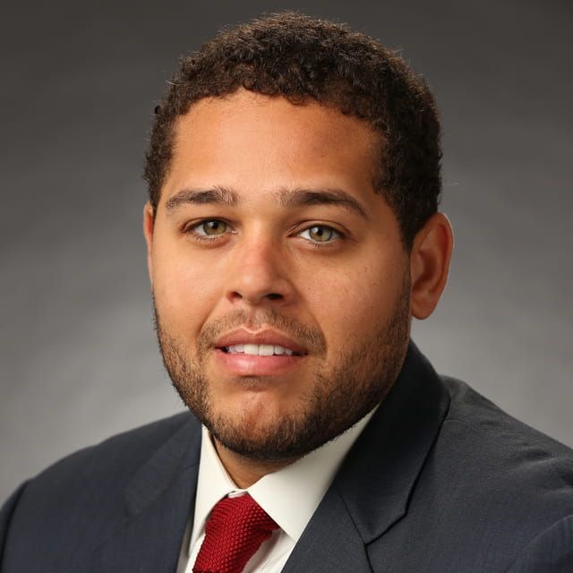 A man in a suit and tie is smiling for the camera