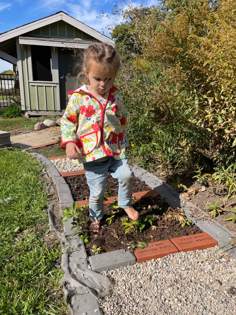 A little girl is standing barefoot on a garden brick road