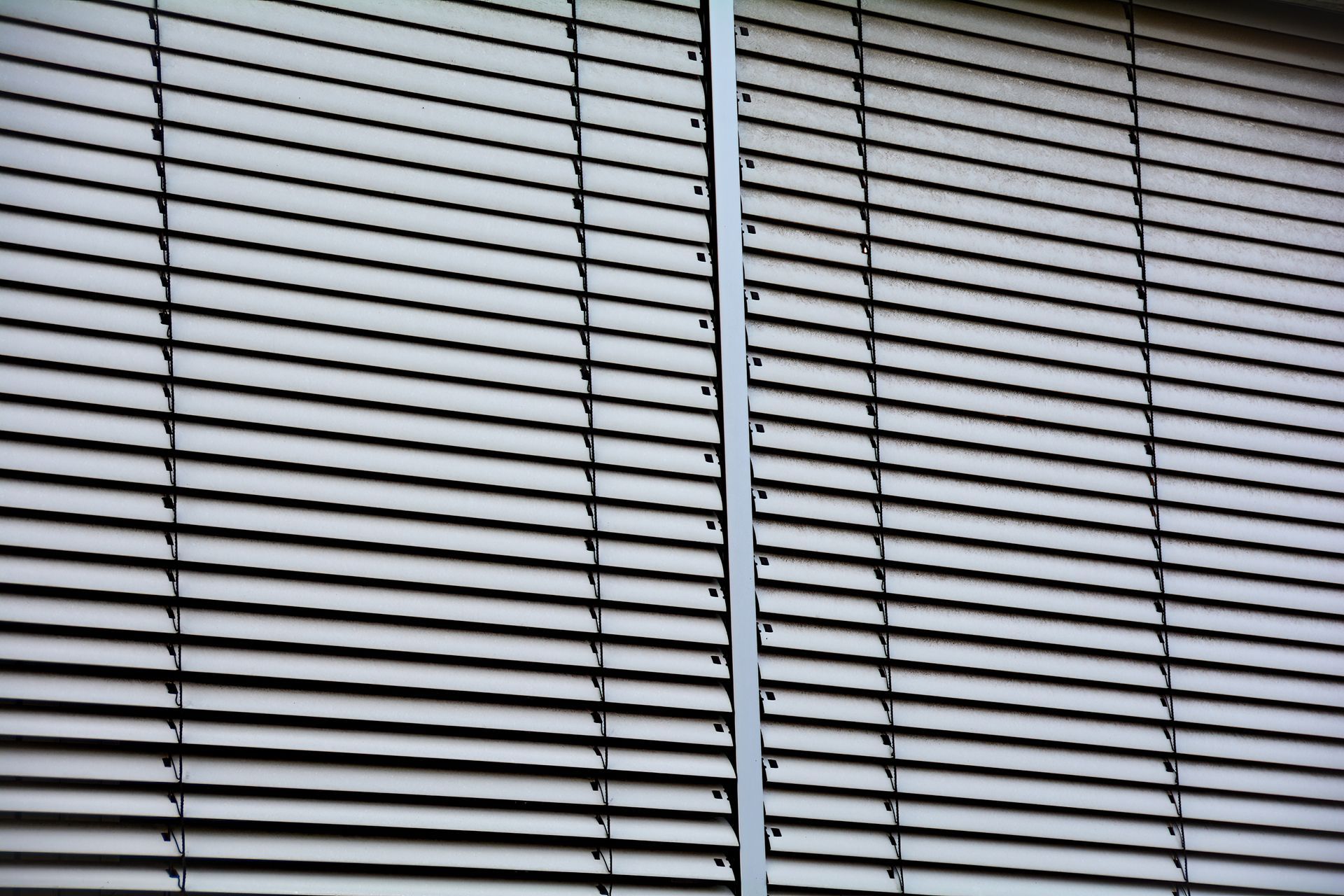 Closed white window blinds with a gray vertical divider
