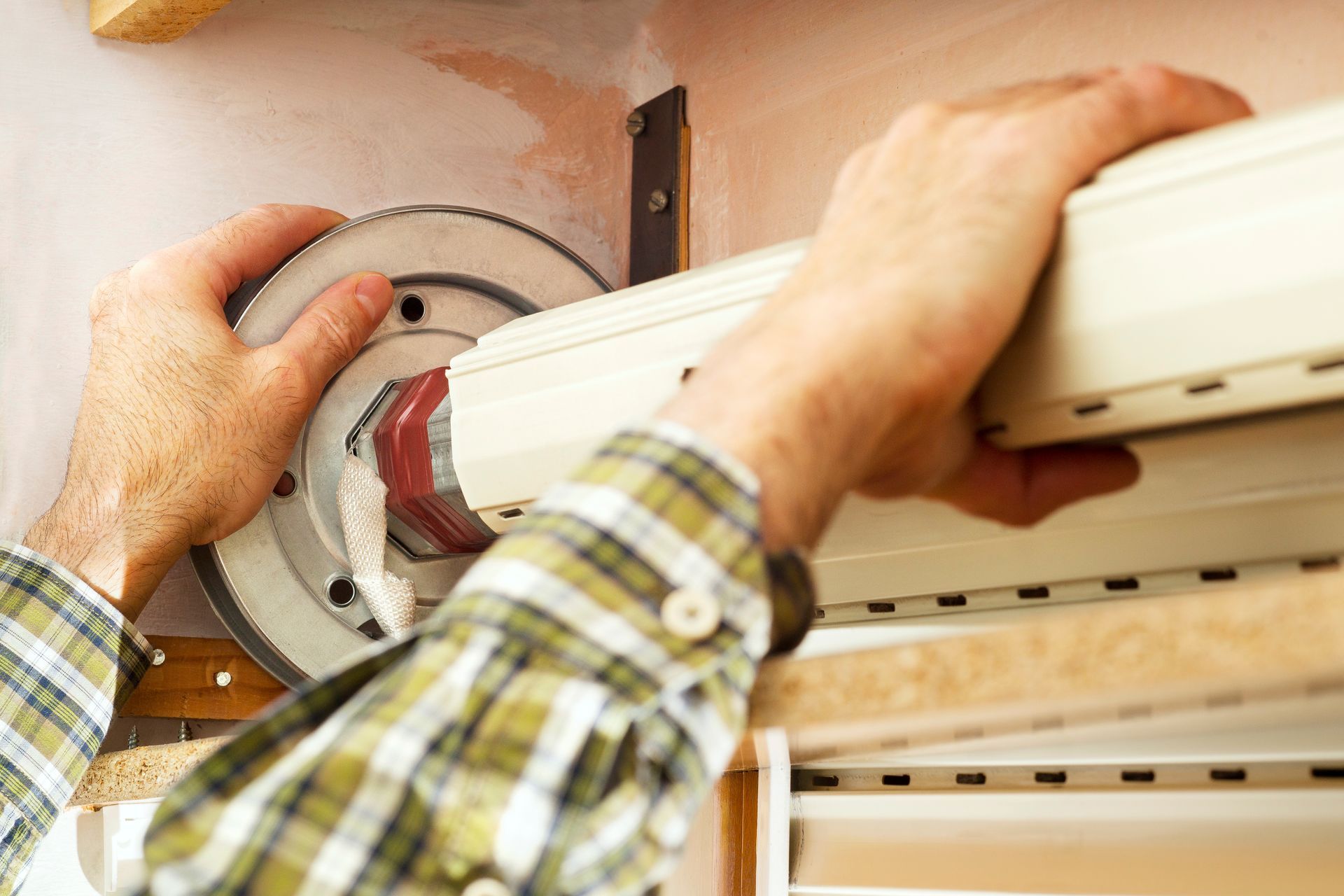 Person installing a white window air conditioner with a screwdriver at a window opening