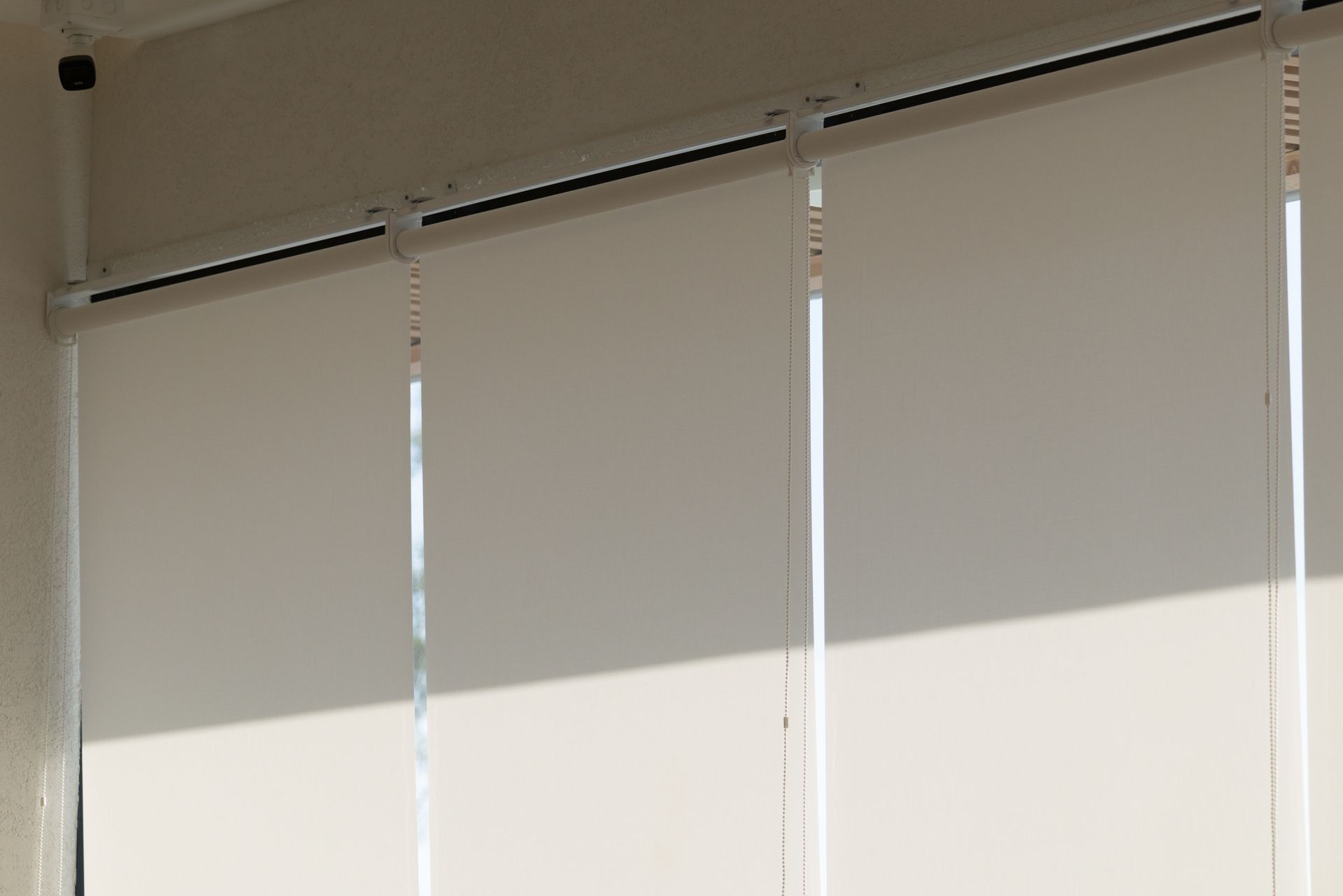 Window blinds partially open, with sunlight casting a bright diagonal shadow across the wall.