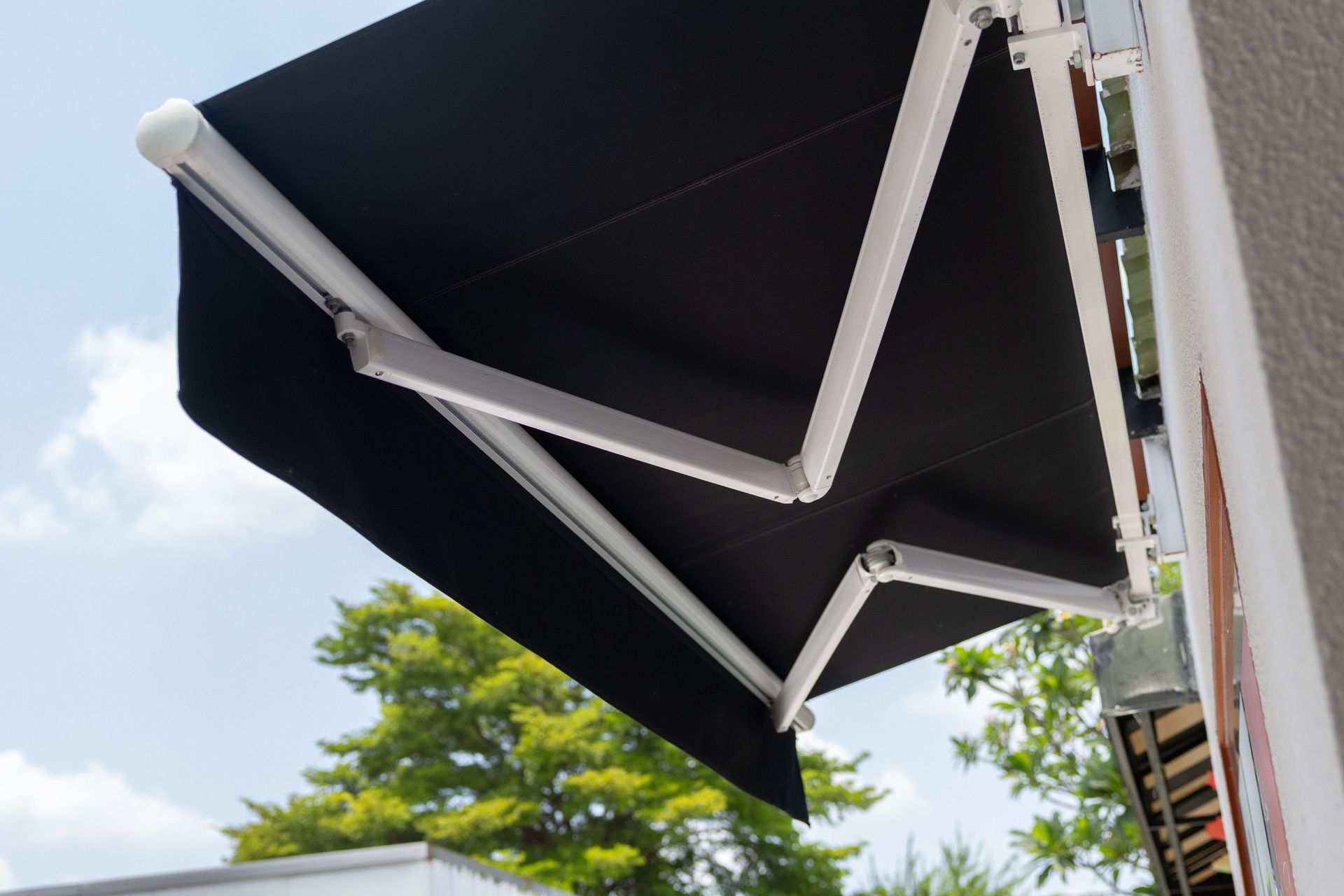 Black retractable awning extended over a building against a blue sky