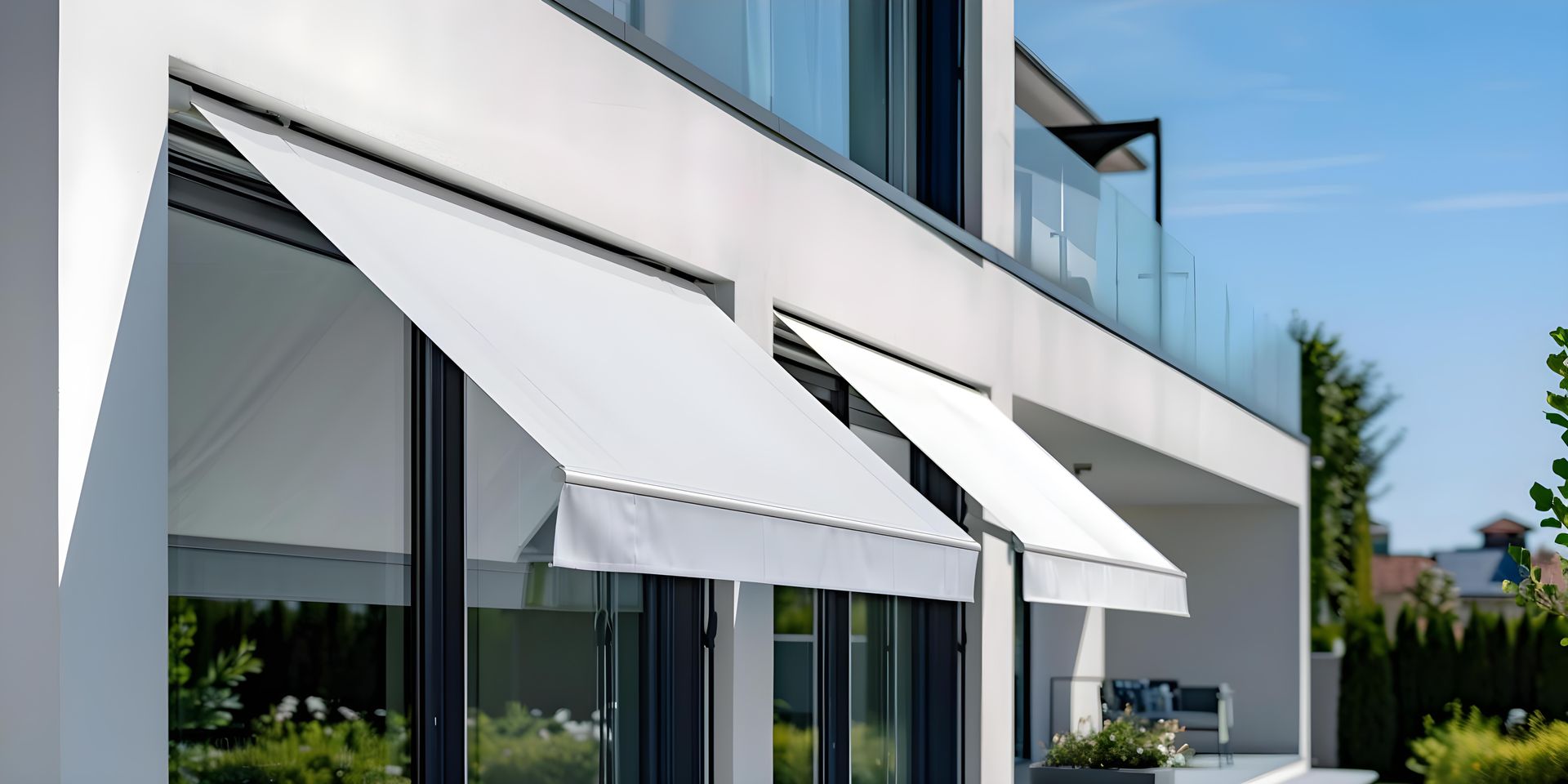 Modern house exterior with white retractable awnings over large glass windows