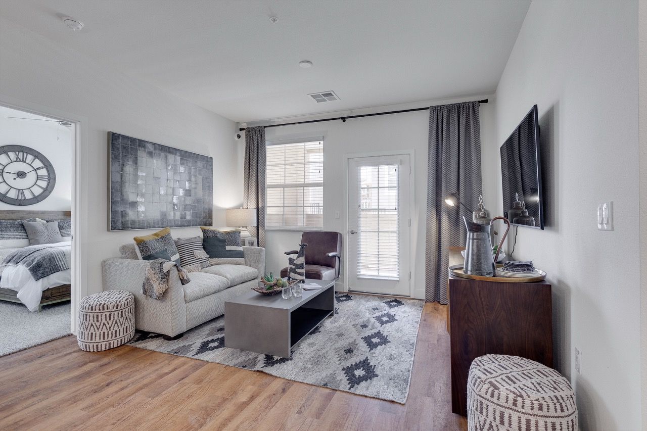 Living room with gray sofa, coffee table, TV, and doorway to bedroom.