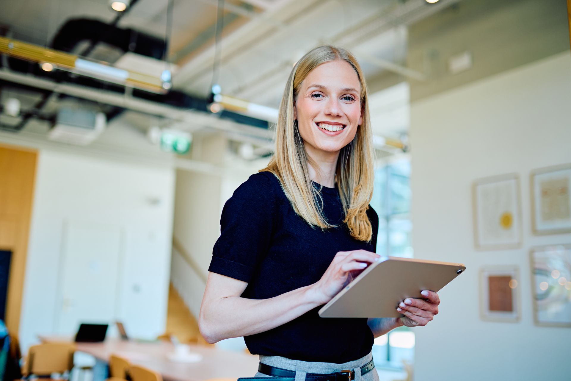 Smiling person holding a tablet in a bright office setting Smiling person holding a tablet in a bright office setting