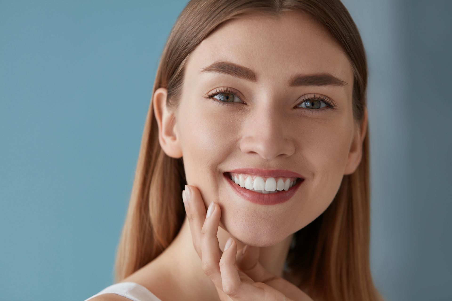 Smiling person touching chin against a blue background