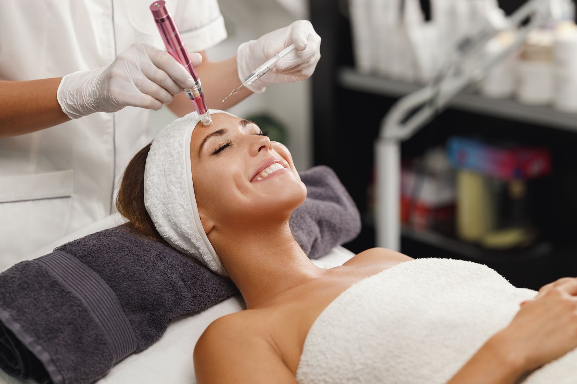 Facial treatment with serum applied to a smiling client lying on a spa bed Facial treatment with serum applied to a smiling client lying on a spa bed