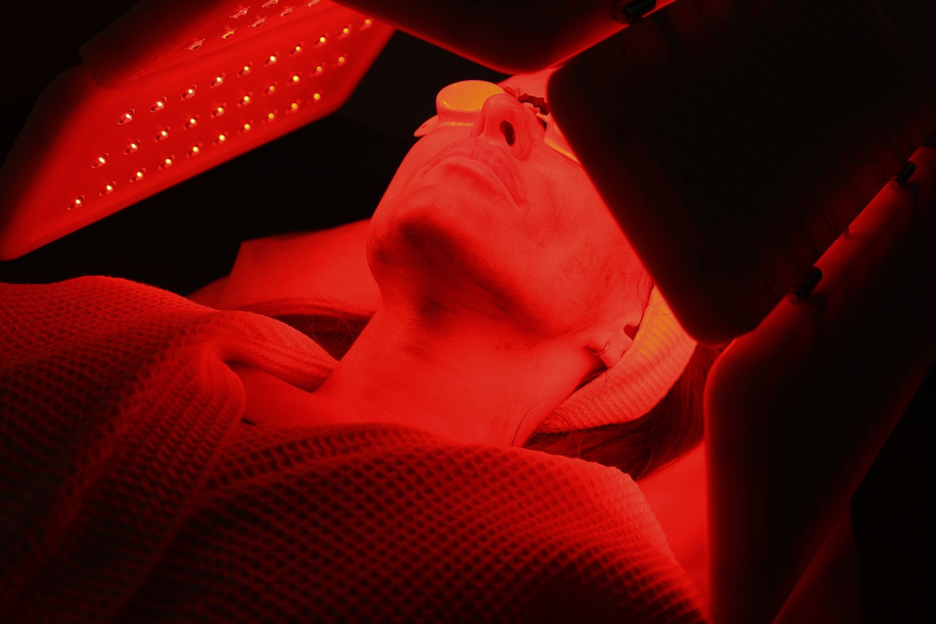 Person lit in red light, reclining or lying down inside a dark, enclosed space. Person lit in red light, reclining or lying down inside a dark, enclosed space.