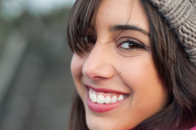 Smiling woman in a knit hat, close-up portrait with blurred outdoor background