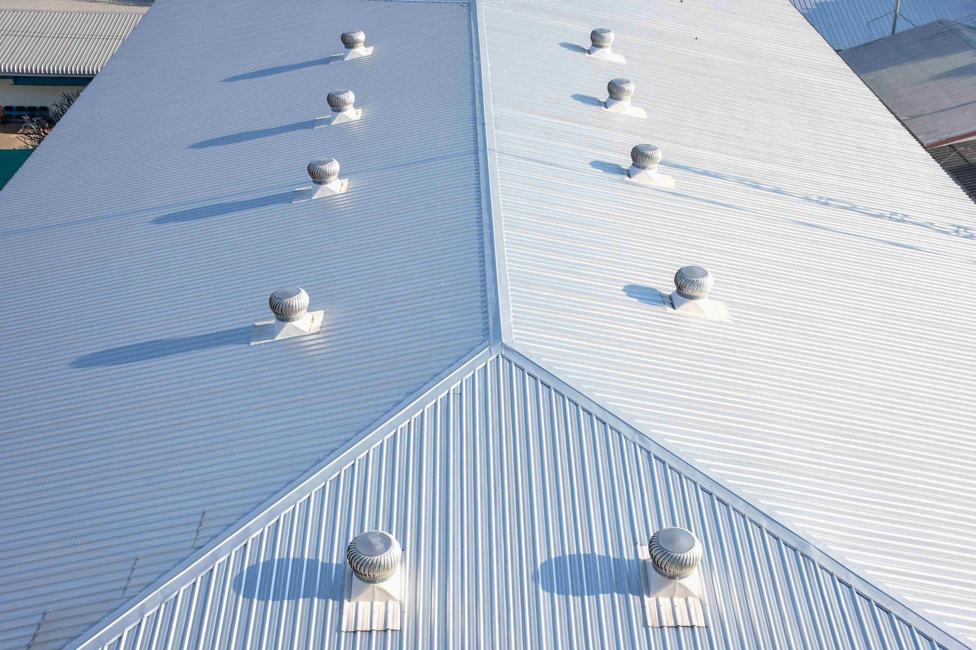 Metal roof with rows of white vent caps and a central seam, viewed from above