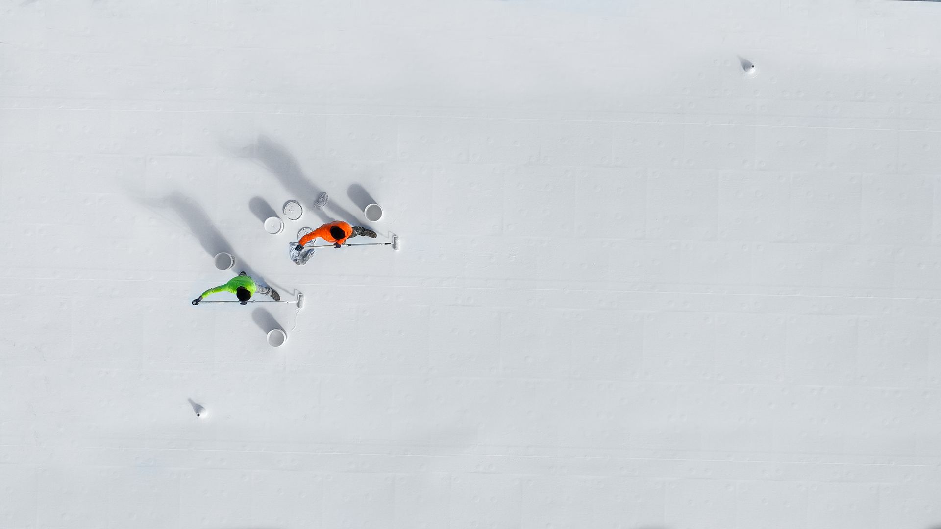 Overhead view of two skiers, one orange, one green, skiing on a snow-covered slope.