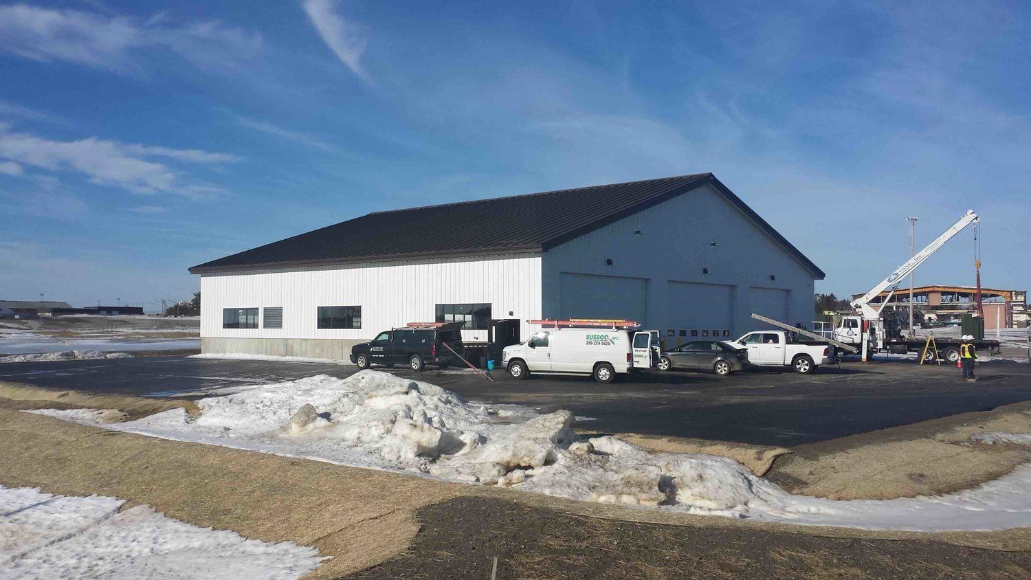 A large white building with trucks parked in front of it.