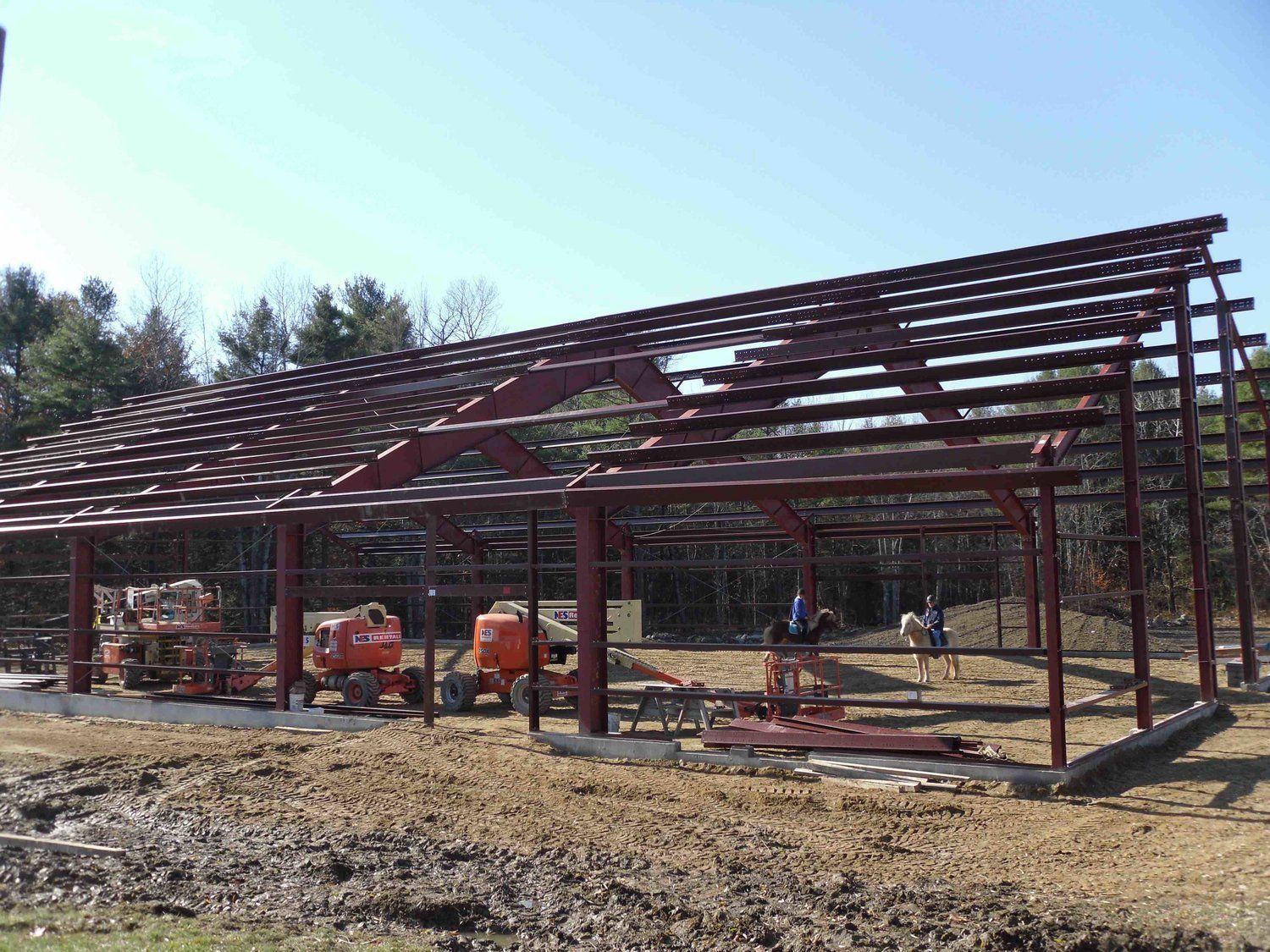 A large metal structure is being built in a muddy field.